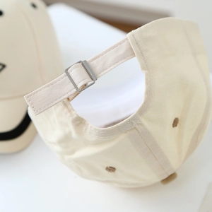 Detail of adjustable metal buckle and stitching on beige cotton kids baseball cap