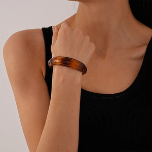 Detail of amber acrylic irregular open cuff bracelet worn by a model on black clothing