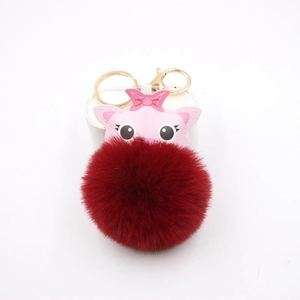 Macro view of cute pink leather pig face and large red faux fur pompom keychain