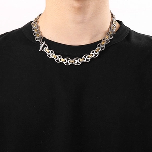 Close-up of a two-tone silver and gold Byzantine chain necklace with T-bar toggle clasp