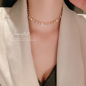 Détail du collier ras du cou élégant en perles et diamants sur un blazer en soie