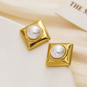 Vintage gold square stud earrings with central white pearls on silk background