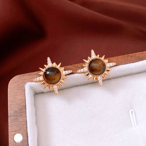 Macro shot of 18K gold plated sunburst stud earrings with brown tiger eye stone