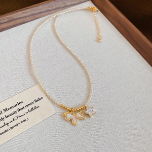 24k gold-plated pearl necklace with small dog and zircon star charms on display