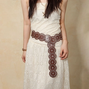 Detail of vintage brown leather belt with metal studs paired with white lace dress