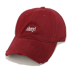 Detail of burgundy cotton baseball cap with white okey embroidery and distressed brim