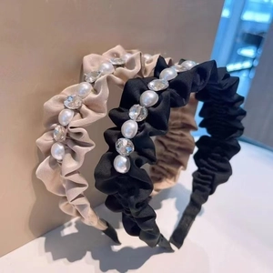 Close-up of pleated satin headbands with faux pearls and faceted rhinestones for women