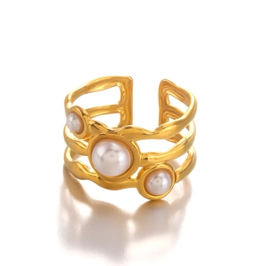 Gold wavy multilayer stainless steel open ring featuring three white pearls on white background