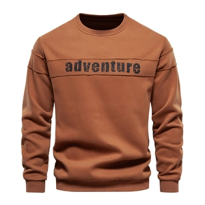 Detail of caramel brown sweatshirt featuring crisp adventure typography and cotton texture
