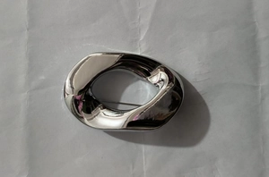 Macro detail of silver geometric irregular brooch with polished surface on white background