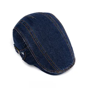 Detailed view of dark blue denim flat cap with contrast stitching and metal buckle