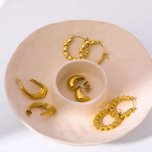 Minimalist 18K gold plated bamboo hoop earrings and stud set on a beige ceramic tray