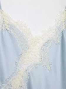 Detailed close-up of light blue satin top with delicate white eyelash lace trim