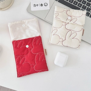 Close-up of quilted fabric pouches in red and cream with rabbit embroidery and snap closure
