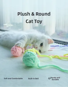 White cat playing with soft colorful yarn balls featuring built-in bells and long tails