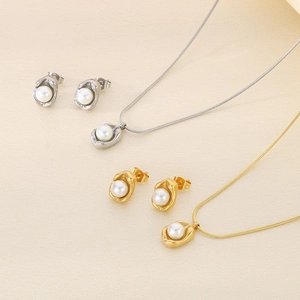 Golden and silver stainless steel jewelry set with shell pearls on beige textured background