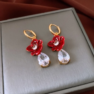 Macro detail of 18k gold earrings with red flowers and teardrop zircon crystals