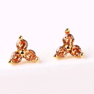 Detail of gold-plated stud earrings featuring three orange-brown zircon stones in a triangle