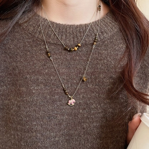 Détail du collier double rang en acier doré avec perles d'oeil de tigre et pendentif poney