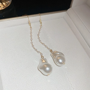 Detail of elegant gold tassel earrings featuring delicate pearls and baroque pendants
