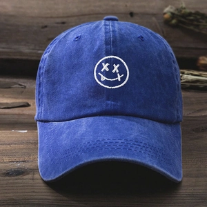 Detail of white embroidered smiley face on washed blue denim baseball cap for unisex