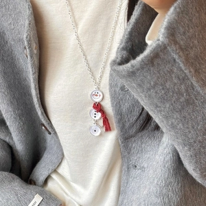 Détail d'un collier bonhomme de neige avec écharpe à pompon rouge sur un manteau d'hiver