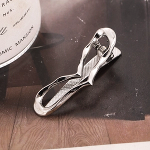 Silver wavy hollow metal hair clip with heart detail on a dark wood background