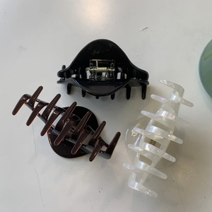 Three acetate claw clips in black, brown, and pearl white on a clean white surface