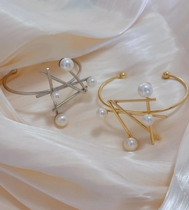 Detailed view of gold and silver irregular geometric cuff bracelets with pearl accents