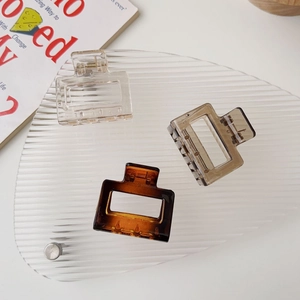 Close-up of three square matte hair claws in amber and tortoiseshell on a textured tray