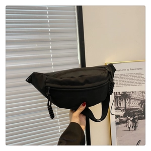 Close-up of black nylon chest bag with knotted zipper pull and adjustable strap