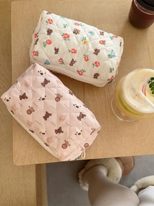 Quilted floral and bear cosmetic bags in cream and pink on a wooden tabletop