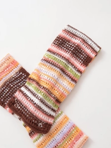 Detailansicht gestrickter Stulpen mit bunten Streifen und glänzenden Pailletten