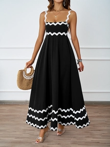 Detail of black maxi dress featuring white wavy trim on straps and hem with chic accessories