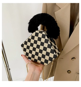Detail of hexagonal checkerboard handbag with plush black handle and gold chain