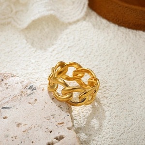 Close-up of 18K gold chain style ring resting on a light textured stone background