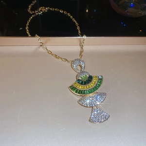 Macro detail of gold fan-shaped necklace pendant with green and yellow gemstones