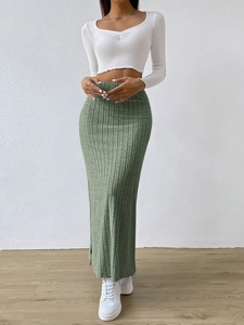 Detail view of green ribbed knit maxi skirt with side slit and high waist texture