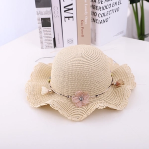Detailed view of kids straw sun hat featuring a wavy brim and pink gauze flower decoration