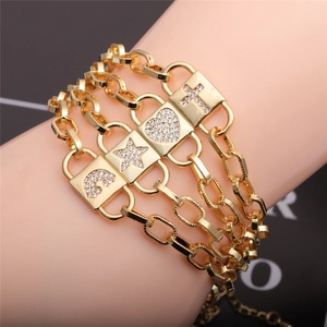 Detail of layered gold bracelet with zircon encrusted cross heart star and moon charms