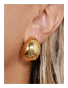 Gros plan de boucles d'oreilles goutte d'eau dorées avec une finition métallique lisse et polie