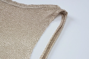 Close-up of beige knitted dress shoulder detail showing glossy weave texture
