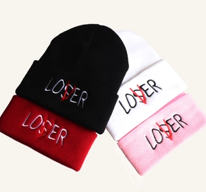 Close-up of knit beanies with Loser embroidery and red V design in multiple colors