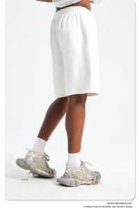 Detail view of white cotton sweatshorts paired with vintage sneakers on a studio background