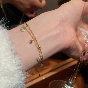 Detailed shot of double-layered 18k gold heart bracelet with sparkling zircon stones