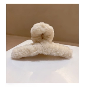 Détail d'une pince à cheveux croisée en peluche blanc crème avec texture fausse fourrure