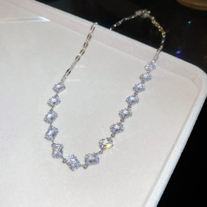 Detail of silver chain necklace with square-cut zircons on beige velvet display tray
