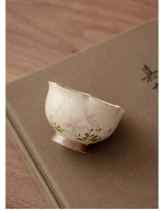 Detail of hand-painted floral ceramic tea cup with wavy rim on vintage book