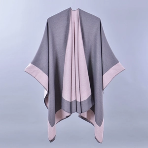 Detail of grey and pink split knit poncho showing dual-tone contrast trim and texture