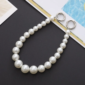 Detail of white pearl strap with silver spring buckles on a black textured background